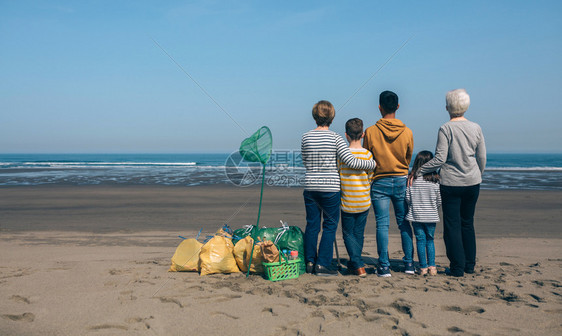 一群志愿者在清理海滩后向看图片
