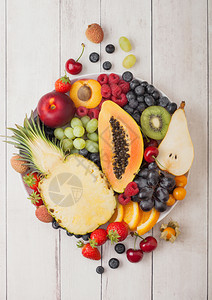 白木本底板上的新鲜生有机夏季果子和异国水菠萝木瓜葡萄内啡橙杏仁基维梨淋巴樱桃和植物图片