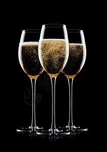 优雅的黄色香槟杯子黑背景的泡和反光图片