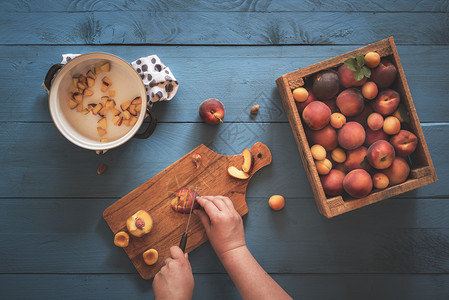 女人亲手切碎桃子和杏从古老的木箱里切开放在蓝色厨房的桌子上面是桃果酱图片