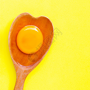 木勺子黄色背景的木勺心形上蛋和白背景