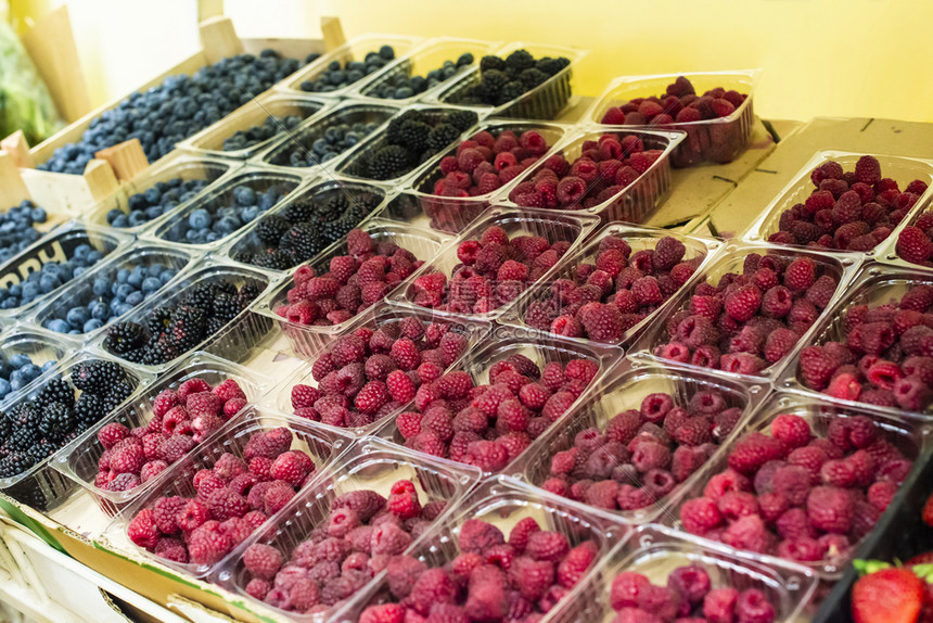 市场货架上的草莓和蓝水果在透明塑料箱中分类图片