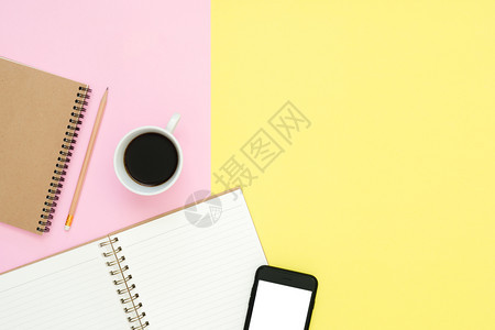 办公桌工作空间平面显示工作空间的顶部有白笔记本页咖啡杯和糊面背景模拟电话粉色彩背景空间概念图片