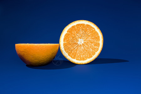 在阳光明亮的蓝背景上红橙子的两半图片