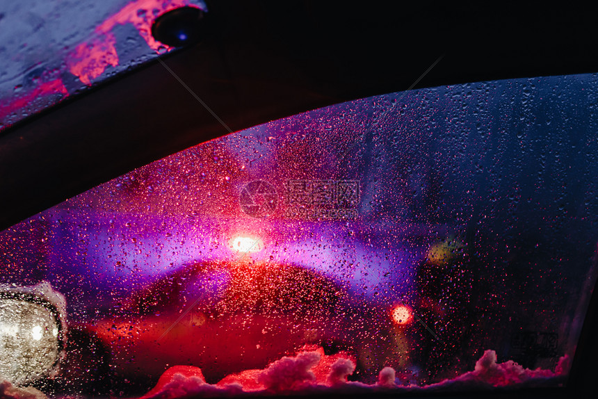 夜晚城市灯光透过挡风玻璃灯和雨下抽象背景水滴图片