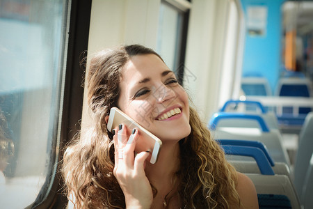 乘坐智能手机火车旅行的城市年轻妇女图片