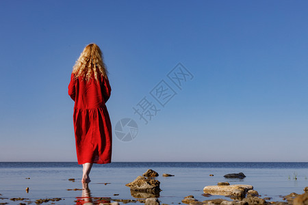 穿着红色长裙的女郎站在大海里图片