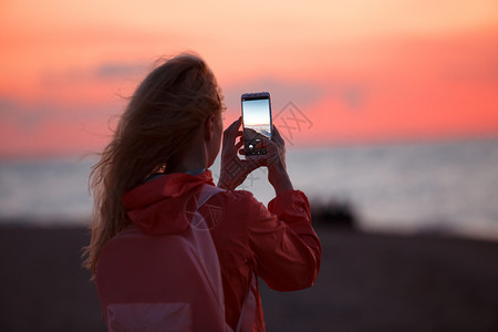 女旅行者使用智能手机拍摄多彩的海日落照片女旅行者使用智能手机拍摄多彩的海日落照片图片