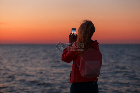 女旅行者使用智能手机拍摄多彩的海日落照片女旅行者使用智能手机拍摄多彩的海日落照片图片