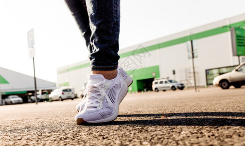 穿着白色运动鞋的妇女站在通往太阳的沥青路上紧闭身穿白色运动鞋的妇女站在通往太阳的沥青路上紧闭图片