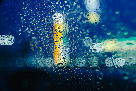 夜晚城市灯光透过挡风玻璃灯和雨下抽象背景水滴图片