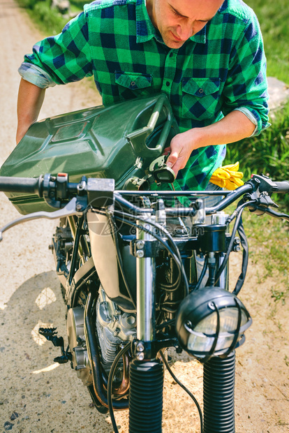 青年男子重新填充户外摩托车的油罐男子再次填充摩托车的油罐图片