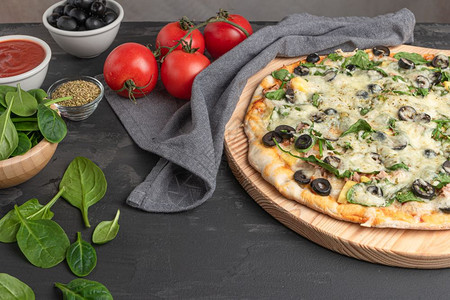 芝士披萨用菠菜西红柿黑橄榄和奶油芝士煮的自制素食披萨背景