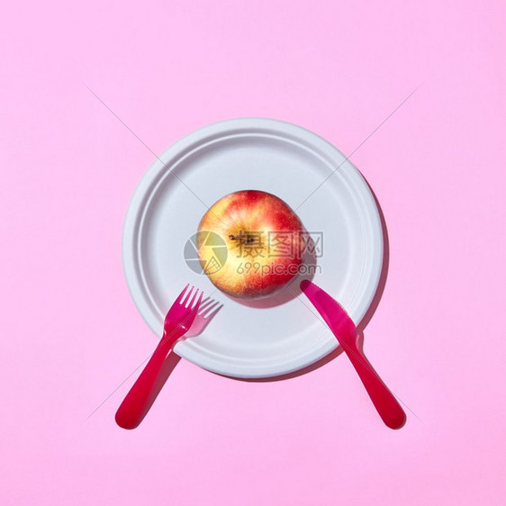 用塑料刀和叉子放在粉红背景上并有复制空间的粉红色背景上顶部视图用塑料刀和叉子放在盘上的新鲜苹果图片