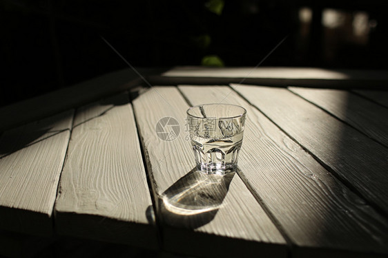 a白桌上的一杯水白桌上有带自然背景的太阳光图片