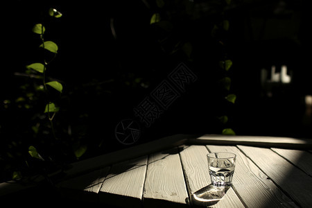 a白桌上的一杯水白桌上有带自然背景的太阳光图片