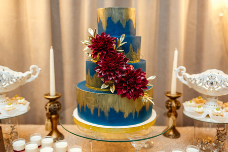 蓝色婚礼蛋糕由盛宴桌边的花朵和沙漠草莓薄饼和蛋糕婚礼接待薄饼糖果棒图片