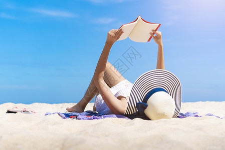 女人在热带海滩上读一本书假期放轻松自由旅行的概念图片