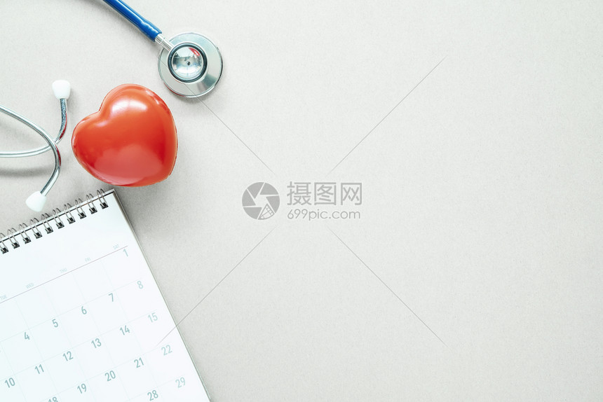 红心听诊器和日历在白桌上有空闲间健康检查规划概念图片
