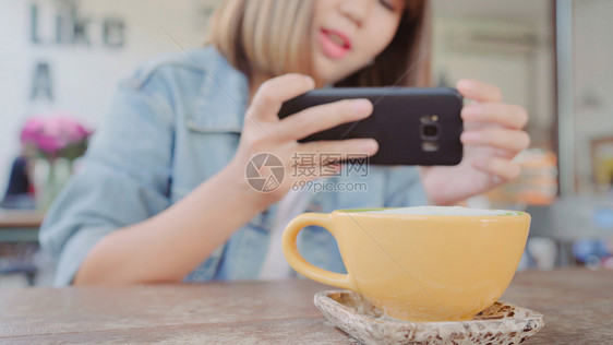 一位年轻女子在智能手机上拍摄咖啡茶图片