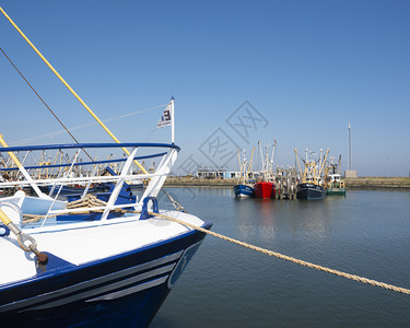 在蓝天下阳光明媚的夏日格伦宁恩岛北边的Lauwersog港的渔船图片
