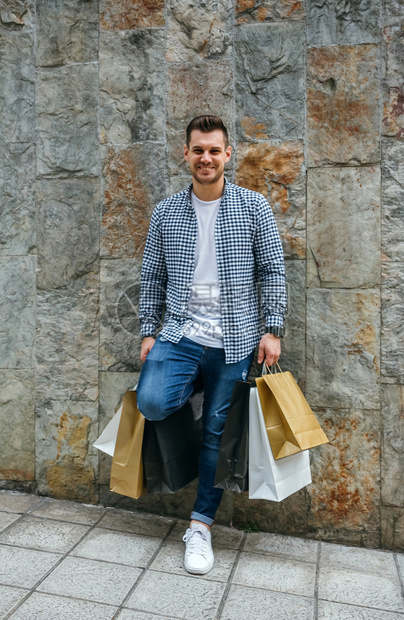 拿着购物袋逛街的青年男子