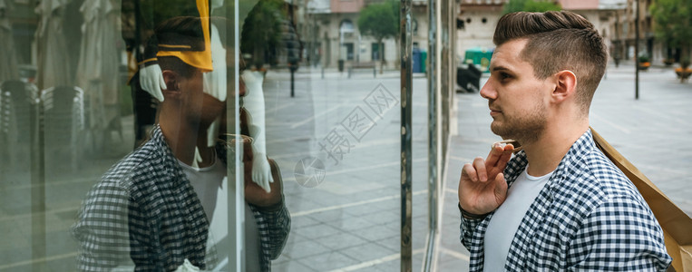 年轻男子的肖像看着时装店的展示男人看着商店的展示图片