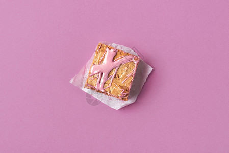 面包纸和粉红色背景上的宝石巧克力单片粉红色巧克力蛋糕上方甜点的微小图象图片
