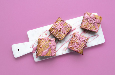 大理石切割板和粉红色背景上的宝石巧克力蛋糕在粉红色巧克力甜点上方平整的红宝石巧克力糖图片