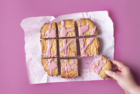 女人在粉红背景上抓住一块粉红巧克力蛋糕在切红宝石巧克力甜点上方吃金发蛋糕图片