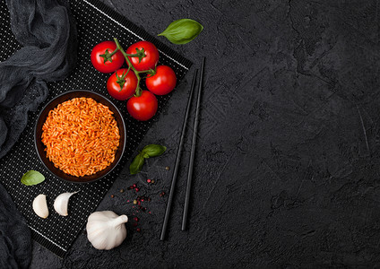 黑盘米碗加西红柿和巴尔大蒜以及黑底的筷子文本空间图片