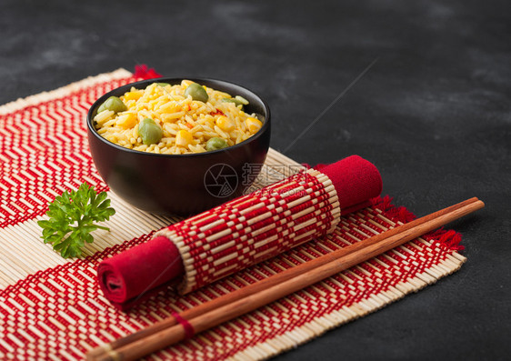 黑碗有煮的机巴斯马提蔬菜大米红竹地上有木棍黄玉米和红辣椒青豆图片