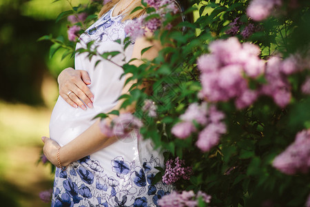 春天一个怀孕的女人对着盛开的树图片