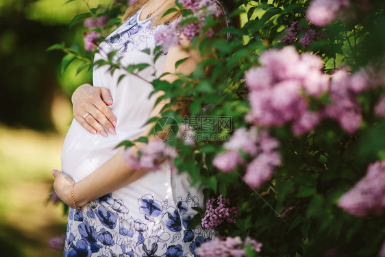 春天一个怀孕的女人对着盛开的树图片