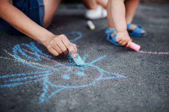 女孩在人行道上画着粉笔小孩在人行道上画着粉笔小女孩在人行道上画着粉笔图片