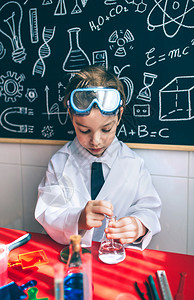小男孩科学家从酒瓶中提取液体用图纸对抗粉笔板图片