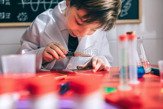 快乐的小科学家看着化液体放大器与画出的黑板对着放大剂快乐的孩子通过放大镜寻找液体图片