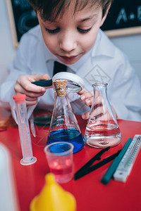 快乐的小科学家们在酒瓶里透过放大器与绘画的黑板对着放大镜寻找丰富多彩的化学液体快乐的孩子通过放大镜寻找液体图片