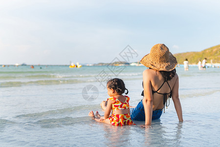 妈和她的孩子晚上在海滩寻找夕阳图片