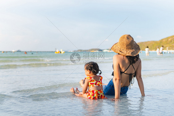 妈和她的孩子晚上在海滩寻找夕阳图片