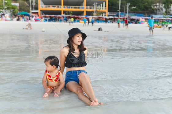 妈和她的孩子晚上在海滩寻找夕阳图片