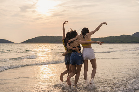 一群青年女人在日落的海边沙滩上开心玩水图片