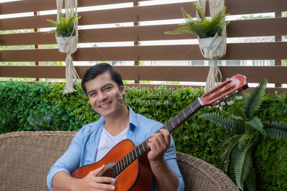 男人弹吉他唱一首歌在花园家微笑图片