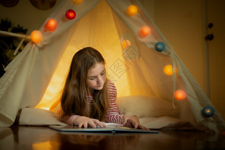 快乐的小女孩读书在家里帐篷露营创意思维概念图片