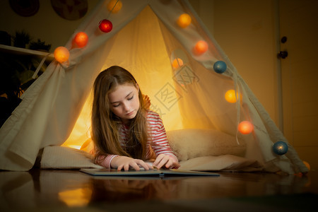 快乐的小女孩读书在家里帐篷露营创意思维图片