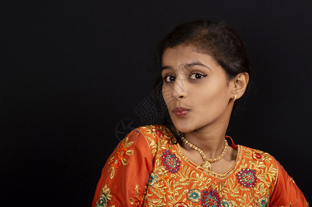 印度女孩一位快乐的印度年轻女孩肖像在黑色背景下大呼小叫她的嘴唇背景