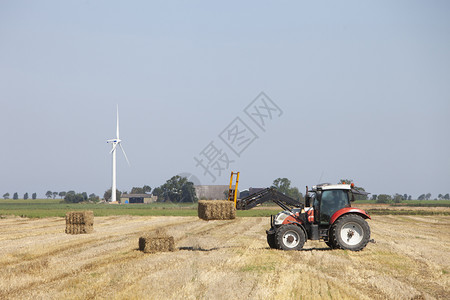 土拉机农夫忙于在荷兰河边的甘金根省杜奇用拖拉机收集干草篮图片