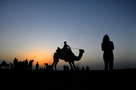 骑着骆驼的人和一个女人剪影图片