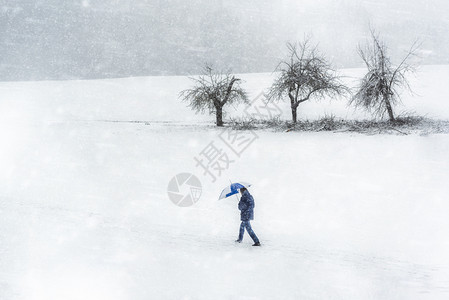 男子在寒冷的黄昏日在德国渡过严寒的冬季暴风雪天恶劣的气景象暴雪和狂风的一天图片