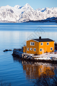 传统的挪威黄木屋站在湖边和远处的山上荒岛北边图片